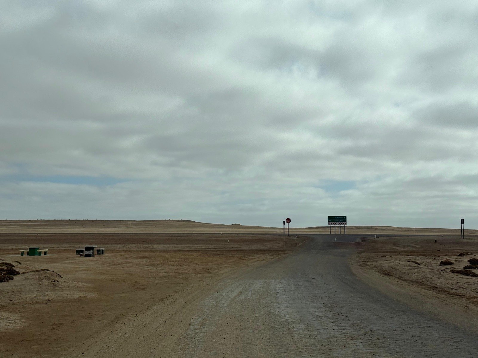 Paesaggio namibiano con strada e veicolo 4x4 in lontananza